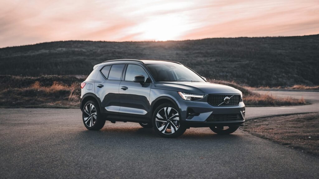 A Volvo SUV parked on a scenic road at sunrise, surrounded by hills. and it's a modern car and in the blog car-safety tech evolution. choose the right car size to find Affordable Car Rentals