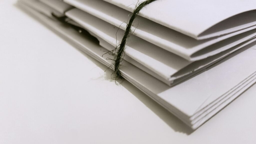 Pile of white envelopes tied with a green string, showcasing a minimalist design. how to rent car?
