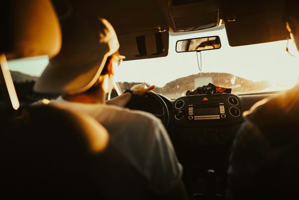 Man driving car with passenger at sunset, capturing warm sunlit atmosphere. rent car fun