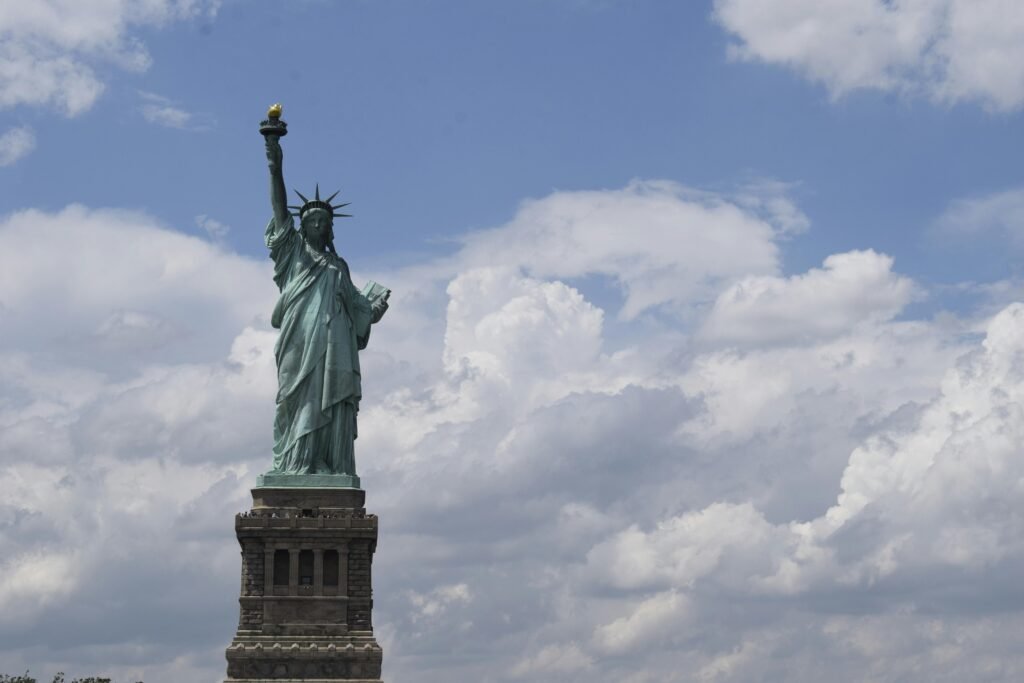 View of the iconic Statue of Liberty with a vibrant blue sky background, symbolizing freedom. REnting car in US blog